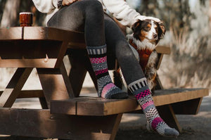 Personne portant des bas Solmate rose et noir en coton recyclé et laine avec son chien